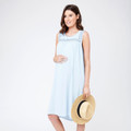 Pregnant model in pale blue sleeveless maternity dress with embroidered yoke detail, holding a straw hat