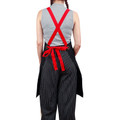 Black and white pinstripe bib apron with red cross-back straps and tie waist, shown from behind