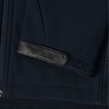 Navy softshell jacket detail showing black leather trim tab and velcro cuff adjustment