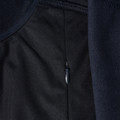 Close-up of navy softshell jacket showing zippered side panel with textured fabric detail and contrast navy fleece interior