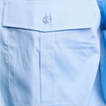 Close-up of pale blue long sleeve shirt showing buttoned chest pocket and epaulette detail