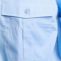 Close-up of sky blue shirt chest pocket with button-fastened epaulette flap and clean topstitching detail