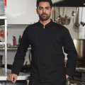 Man wearing black long-sleeve chef jacket with mandarin collar and hidden snap front in professional kitchen