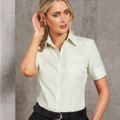 Woman wearing mint green fine-stripe short sleeve button-up shirt with chest pocket and pointed collar
