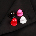 Four chef coat buttons in black, pink, red and white displayed on dark jacket lapel
