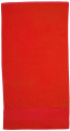 Flat lay of a bright red cotton velour beach towel with contrast hemmed border panel