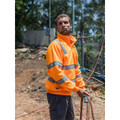 Man on construction site wearing hi-vis orange quarter-zip fleece pullover with silver reflective tape on chest and sleeves