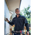 Male tradesperson on building site wearing navy soft shell jacket with reflective piping and full-length zip