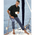 Man on sailboat wearing slate blue jean-style chino pants with rolled cuffs, paired with a black polo