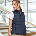 Woman wearing a navy quilted puffer vest with stand collar, zip front and side pockets over a white tee