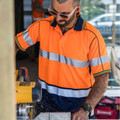 High visibility orange and navy polo with reflective tape across chest and sleeves, featuring contrast collar trim