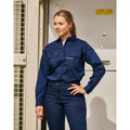 Woman wearing navy long sleeve work shirt with chest zip pockets and point collar in industrial setting