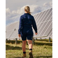 Woman walking near solar panels wearing navy long-sleeve stretch ripstop work shirt, rear view