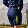 Rear view of navy women's stretch cargo shorts with lime green zip-open thigh vent pocket, worn outdoors