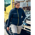 Woman in navy quilted puffer jacket with yellow zip trim, worn near a work vehicle in a trade site setting