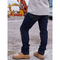 Model wearing dark indigo stretch denim cargo jeans with black panel knee reinforcements on a worksite