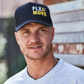 Man wearing black structured trucker cap with embroidered yellow and white logo on smooth front panel