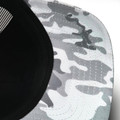 Underside detail of black trucker cap with snow camo patterned brim in white and grey tones