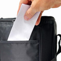 Hand placing a card into the front pocket of a charcoal multi-bottle cooler bag with zip closure