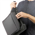 Black insulated cooler bag with adjustable carry strap held against charcoal grey henley shirt