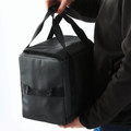Charcoal grey insulated cooler bag with black webbing handles and front slip pocket held by person