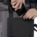 Hands placing smartphone into front pocket of charcoal Stormtech Salt Spring 16 leak-proof cooler bag with reinforced black panel and webbing straps