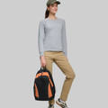Woman holding black and orange structured backpack with reflective piping details by handle