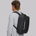 Male model wearing a black water-resistant backpack with white zip pull and structured front pocket