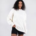 Oversized cream crew neck sweater with dropped shoulders and relaxed fit worn with black shorts