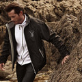 Black softshell jacket with grey contrast hood and trim, featuring zippered pockets and embroidered chest logo