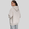 Back view of oversized pale grey hoodie with hood up, loose fit and wide ribbed cuffs, paired with grey sweatpants