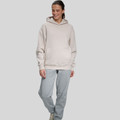 Woman wearing oversized cream hoodie with hood and kangaroo pocket paired with grey marle fleece pants