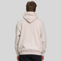 Back view of model wearing an oversized sand pullover hoodie with ribbed hem and large hood