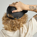 Black unstructured dad hat with brass-tone buckle closure and embroidered eyelets