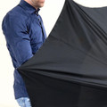 Hands holding expandable charcoal grey umbrella canopy with navy blue long-sleeve shirt visible