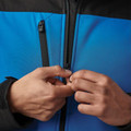 Close-up of azure blue and black softshell jacket showing YKK-style centre-front zip and chest zip pocket detail