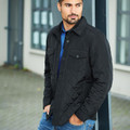 Man wearing black quilted insulated jacket with shirt collar, chest pockets, and button front