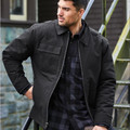 Man wearing black insulated work jacket with point collar, front zip, and chest pocket over plaid shirt