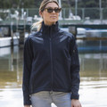 Woman wearing a navy softshell jacket with stand collar, full-zip front and sleeve zip pocket at a marina