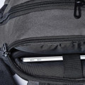 Close-up of charcoal grey backpack showing open laptop compartment with slim silver laptop and black zip detailing