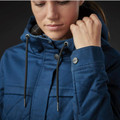 Woman adjusting navy blue quilted insulated jacket hood with black drawcords and branded snap cuff detail