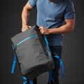 Man handling a charcoal roll-top backpack with electric blue zip and shoulder straps, opening main compartment