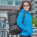 Woman carrying black 35L waterproof duffel bag with welded seams and padded shoulder strap, urban setting
