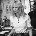 Woman wearing white button-up shirt with contrast check cuffs and dark buttons, sleeves rolled, kitchen setting