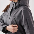 Woman wearing charcoal grey waterproof system jacket with adjustable hood, zip chest pocket and sleeve utility pocket
