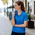 Woman wearing a royal blue short-sleeve performance polo with spread collar and button placket, outdoors