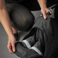Model opening separate shoe compartment of black 32L nylon duffle bag revealing stored sneakers