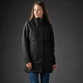 Woman wearing black Stormtech mid-length 3-in-1 waterproof jacket with structured hood and concealed zip placket
