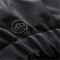 Close-up of black quilted jacket fabric with tonal rubberised logo badge detail