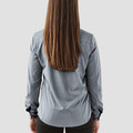 Rear view of woman wearing a slate grey long sleeve performance shirt with shoulder seam detailing and cuffed wrists
